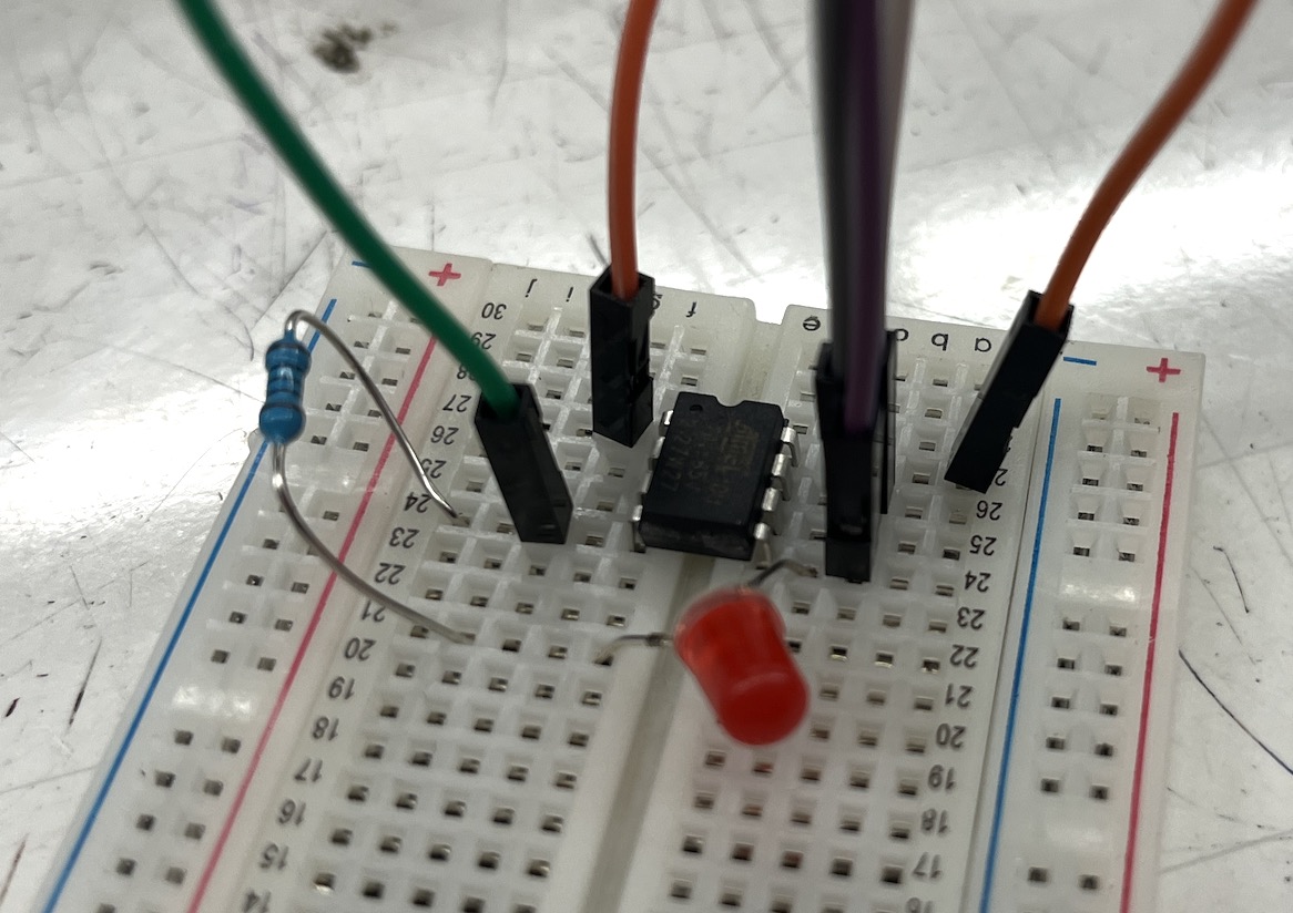 Breadboard with the ATtiny wired to jumper cables plus a red LED and resistor for the Blink test