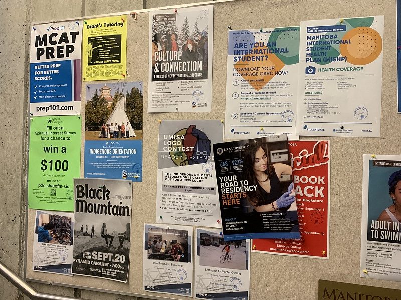 Campus bulletin board crowded with flyers for tutoring, MCAT prep, student clubs, and events
