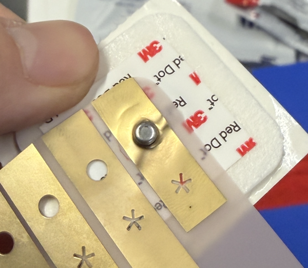 Gold flex strip snapped onto the metal stud of a 3M Red Dot gel electrode, held between fingers