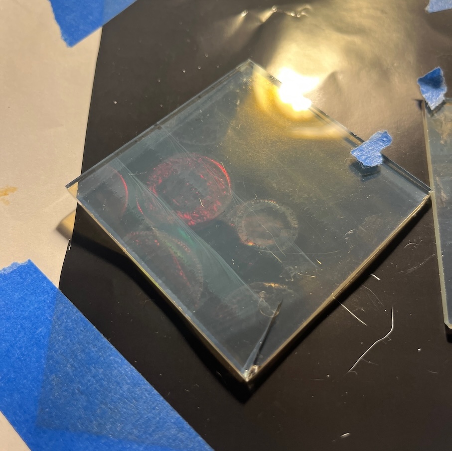 Developed glass hologram plate showing faint reddish images of coins floating within it