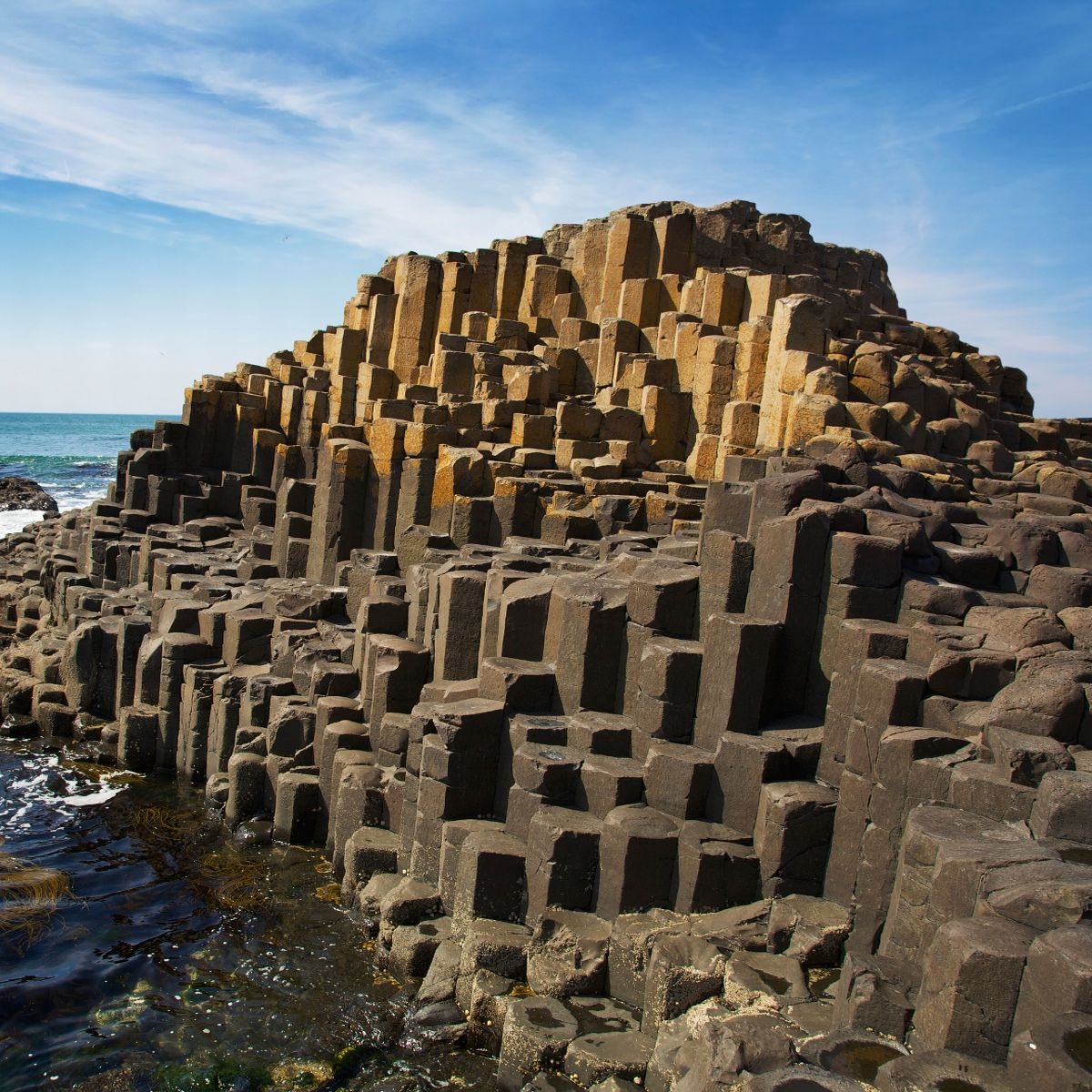 Hexagonal basalt columns of the Giant's Causeway rising from the sea under a blue sky
