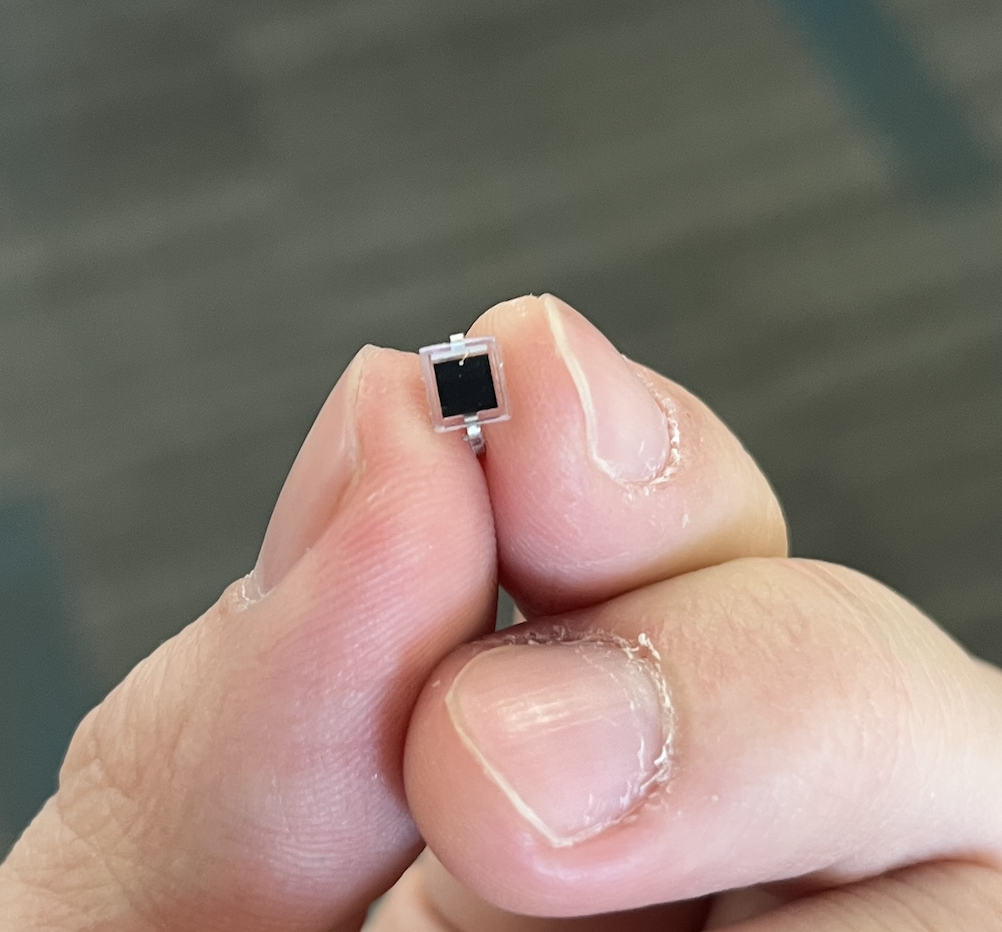 Fingertips pinching the tiny black BPW34 photodiode to show its small size