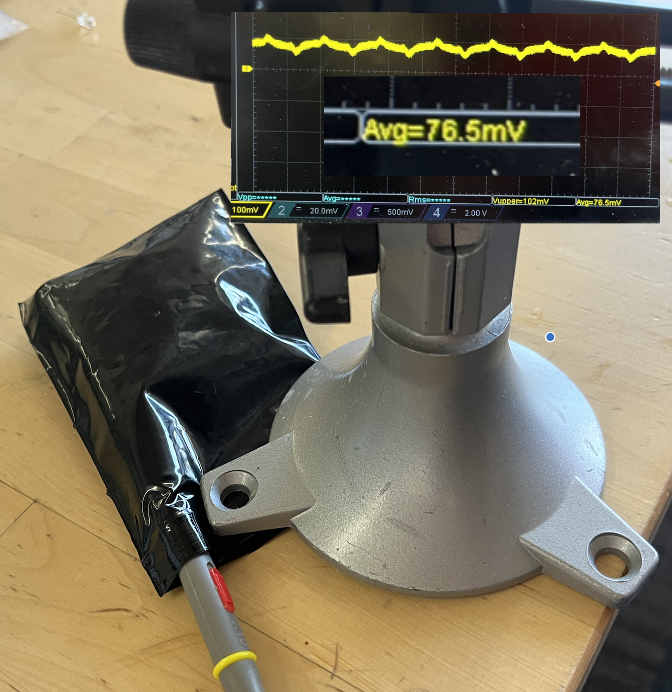 Photodiode leads inside a black bag with an oscilloscope overlay reading Avg 76.5mV