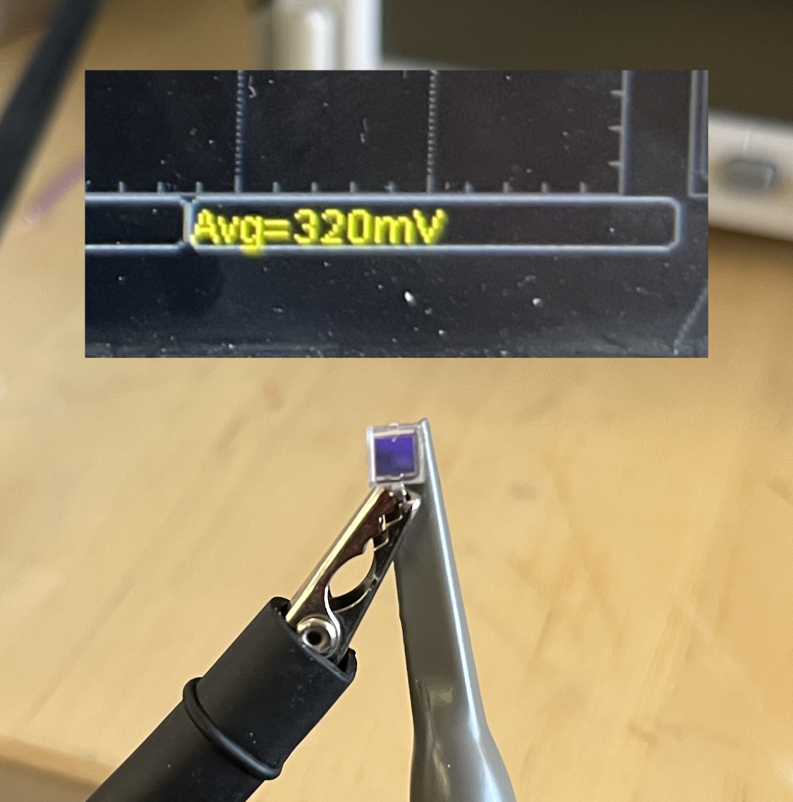 Alligator clip holding the BPW34 in indoor light with an oscilloscope overlay reading Avg 320mV