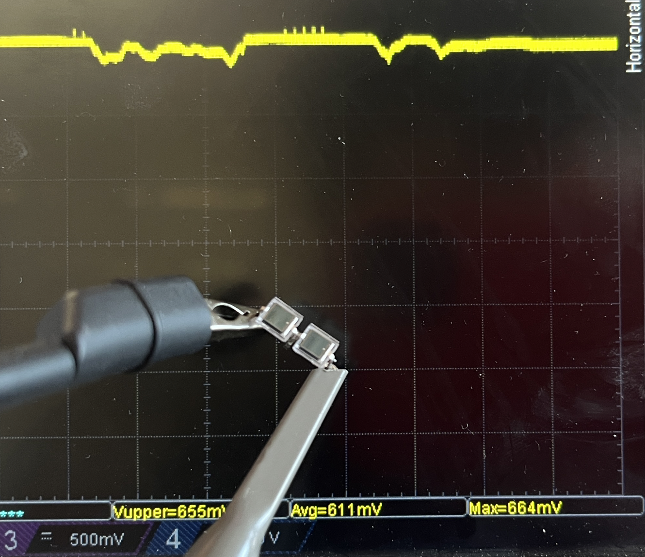 Two BPW34 diodes soldered in series held against an oscilloscope reading Avg 611mV