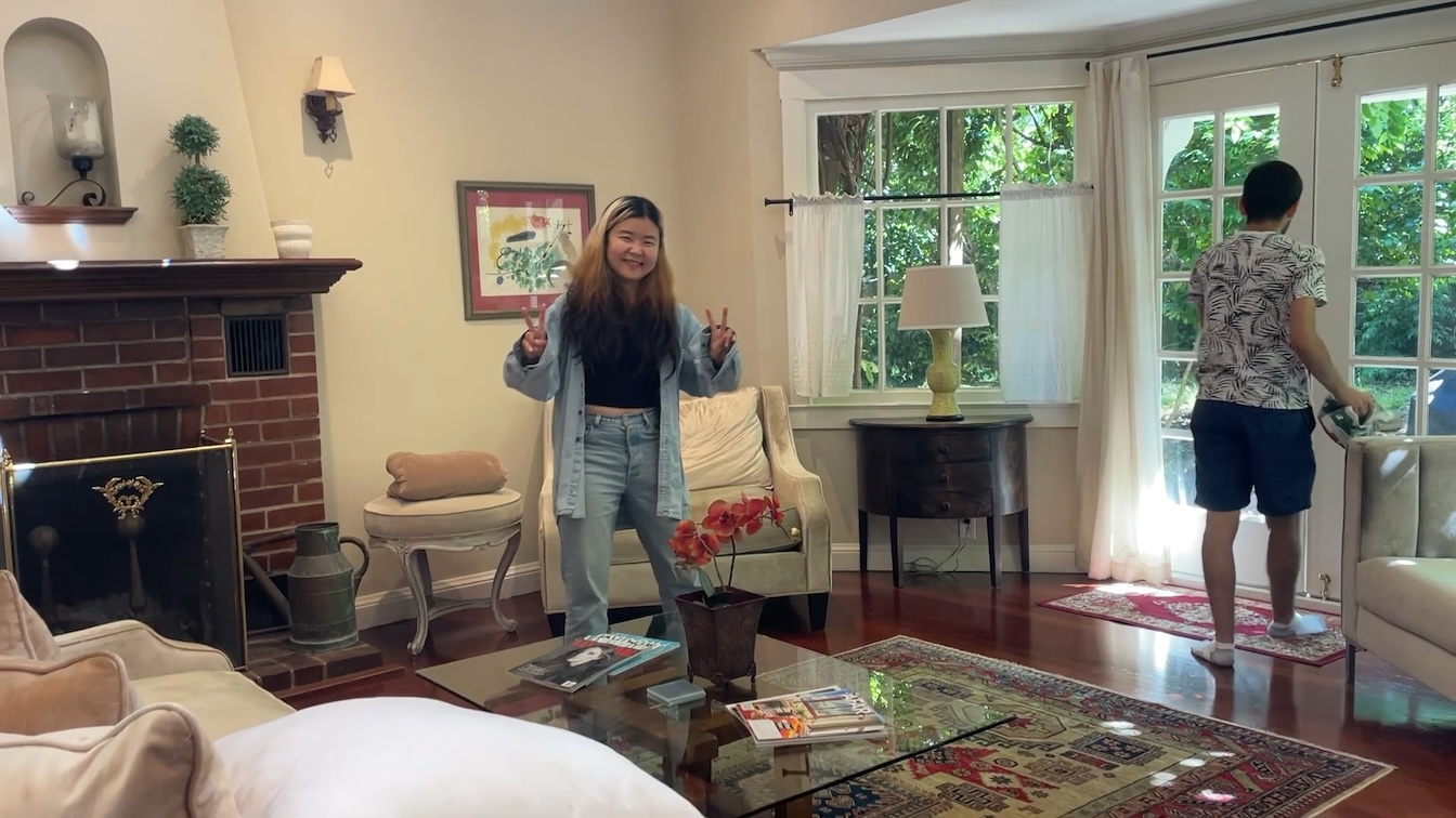 Woman flashing peace signs in the Mill Valley house living room while someone opens the patio doors
