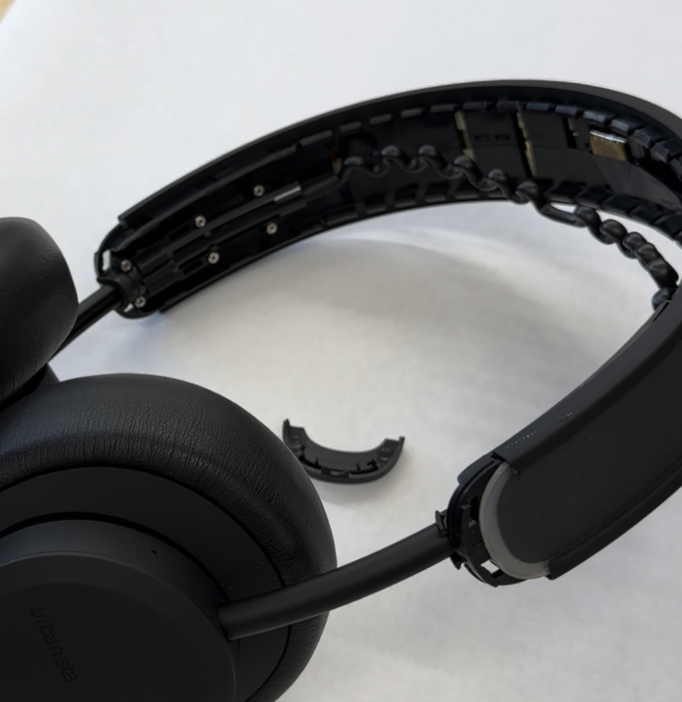 Headband with its snap-fit covers popped off, exposing the strain-relieved cable running through it
