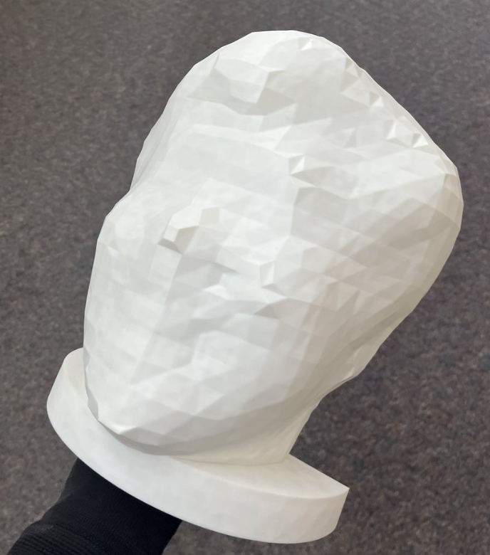 Hand holding a large 3D-printed low-poly head, the mold master for the big head candle